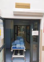 Korytarz szpitala, na łóżku transportowym leży kilkanaście zgrzewek  wody( źródło: PUS Wrocław)